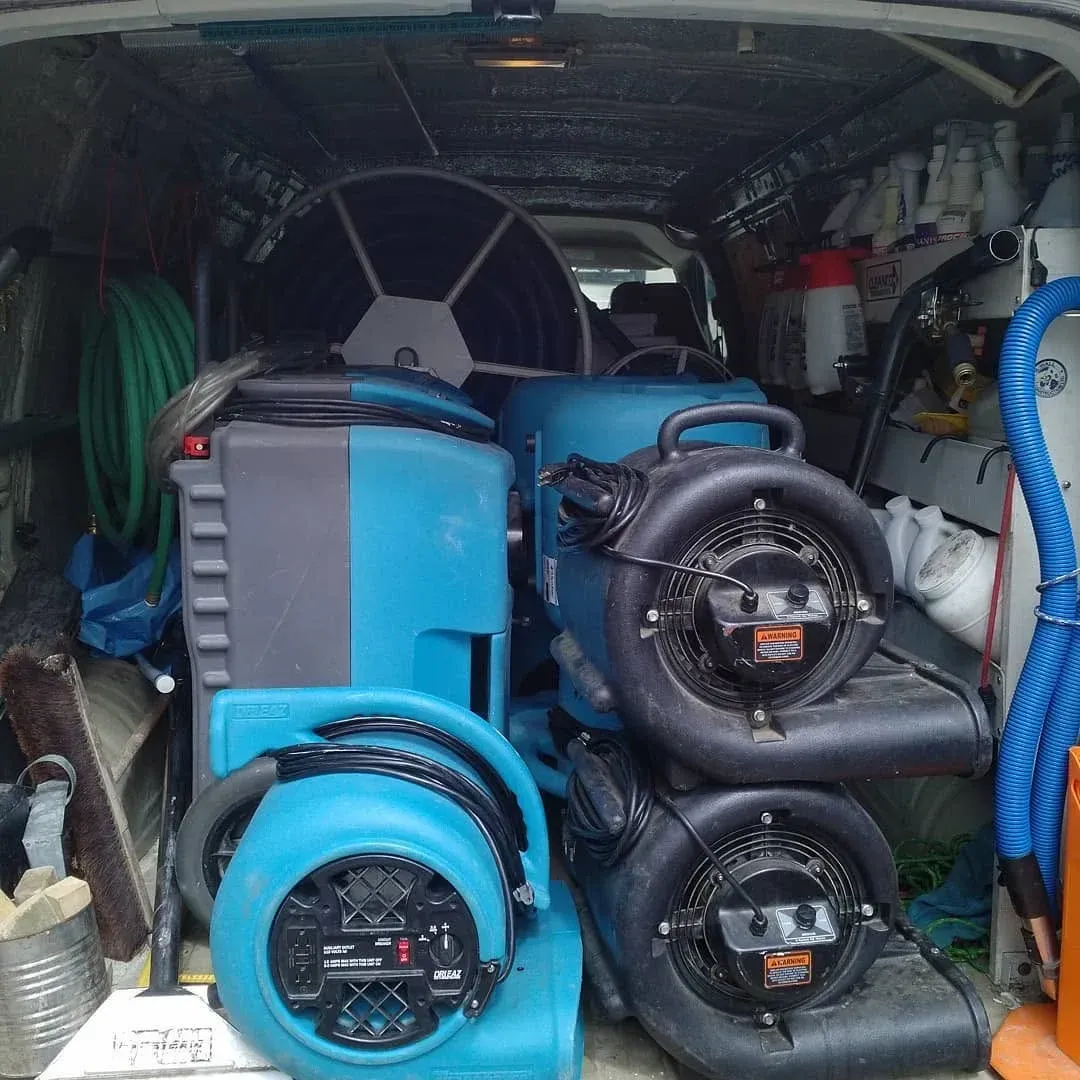 Van loaded with blue industrial equipment, hoses, and fans packed inside.